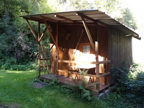 A wooden cabin with a porch, surrounded by greenery. - Cottage 'Gîte Pause Rando' with Private Terrace and Private Garden (Merviller)