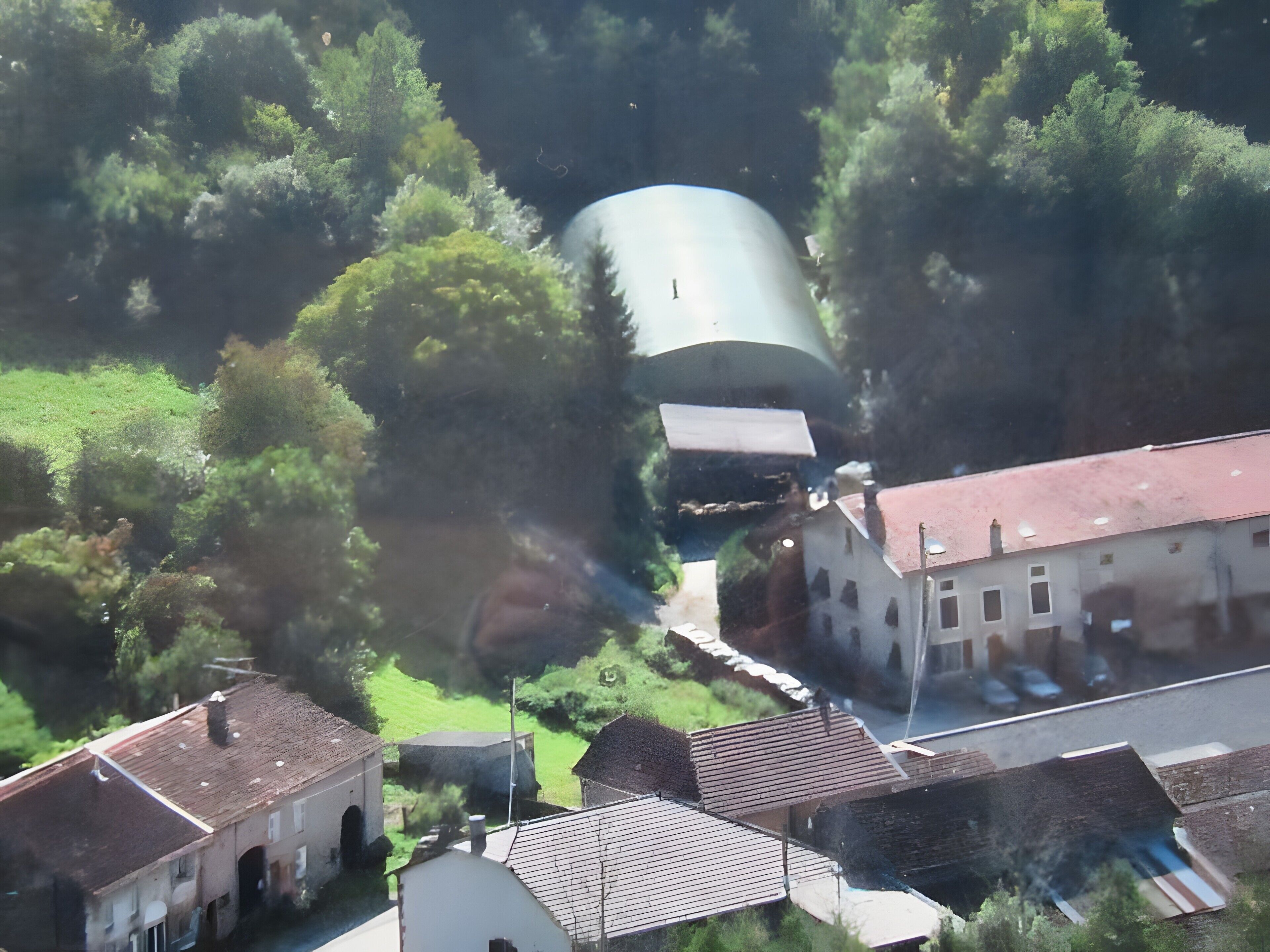 A cylindrical structure amidst a residential area with buildings and greenery.