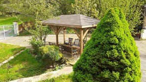 A gazebo with a roof and seating area, surrounded by well-maintained greenery and a stone pathway. - Cottage 'Gîte Pause Rando' with Private Terrace and Private Garden (Merviller)