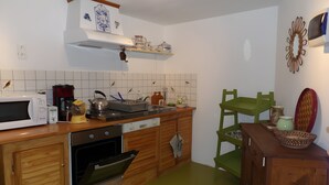 A kitchen with wooden cabinets, a microwave, a kettle, and a coffee maker.