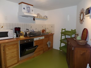 A kitchen with wooden cabinets, a microwave, a kettle, and a coffee maker.