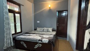 A bedroom with a bed, a ceiling fan, a window with curtains, and a door.