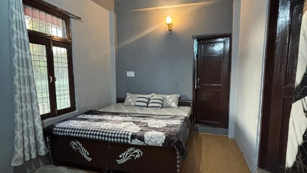 Une chambre à coucher avec un lit, un ventilateur de plafond, une fenêtre avec des rideaux et une porte.