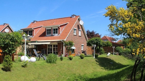 A two-story house with a red-tiled roof, a front porch, and a well-maintained lawn. - Holiday home in Aurich with swimming pool (Aurich)