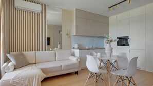 Una sala moderna con un sofá, una mesa de centro y un comedor con sillas.
