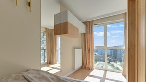 A modern bedroom with a large window, a bed, and a built-in wardrobe.