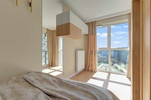 A modern bedroom with a large window, a bed, and a built-in wardrobe. - Nowa Letnica - Gdansk Seaside (Gdańsk)