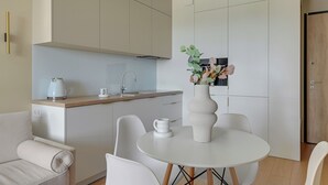 Una cocina moderna con una mesa de comedor redonda, sillas blancas y un florero con flores.