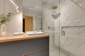 A modern bathroom with a marble vanity, dual sinks, a shower with a glass enclosure, and a heart-shaped mirror. - Nowa Letnica - Gdansk Seaside (Gdańsk)