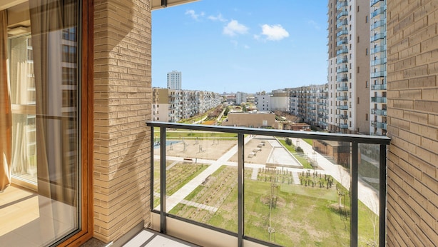 A balcony with a view of a residential area, including apartment buildings and a park.