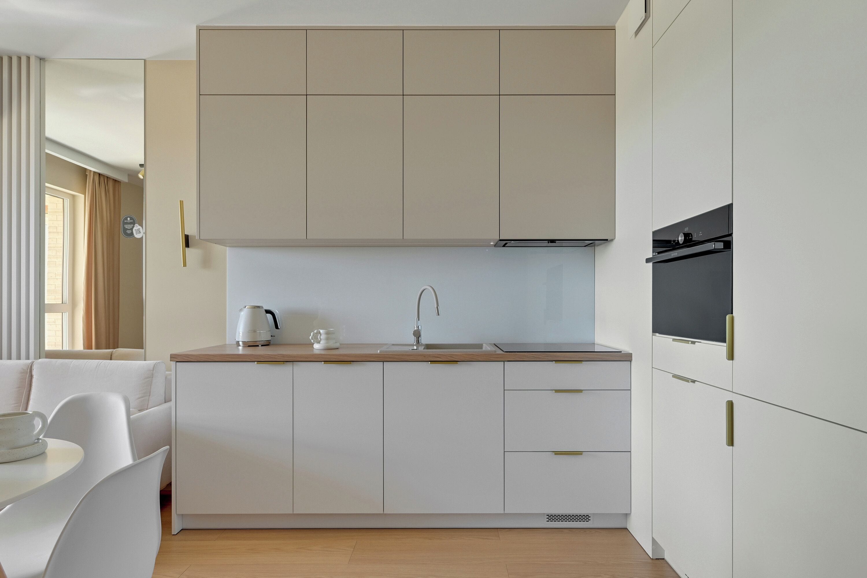 A modern kitchen with white cabinetry, a wooden countertop, and a built-in oven.