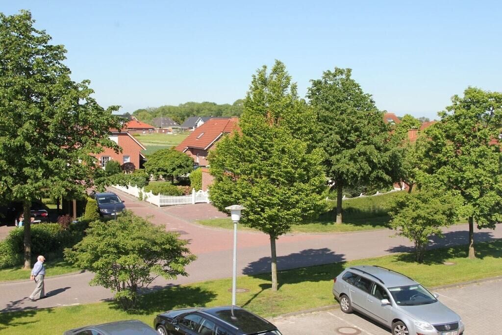 Een woonwijk met geparkeerde auto's, huizen en bomen.