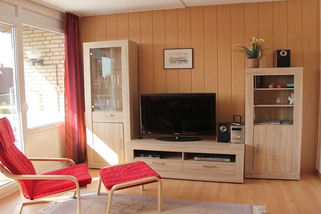 A living room with a television, wooden cabinets, and a red chair.