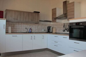 A kitchen with white cabinets, a coffee maker, and a stove. - House Behind the Dike I (Hooksiel)