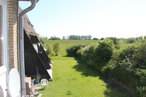 A residential property with a sloped roof, a visible chimney, and a well-maintained lawn. - House Behind the Dike I (Hooksiel)