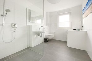 Ein modernes Badezimmer mit Duschkabine aus Glas, einem weißen Waschbecken und einer Toilette.