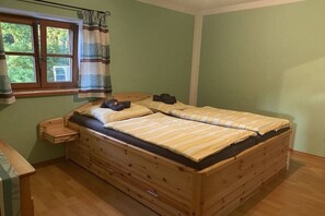 A wooden bed with storage drawers, a bedside table, and a window with curtains. - At the Shoemaker's Garden (Lohberg)