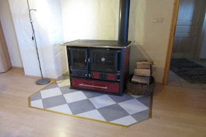 Ein Zimmer mit Kaminofen, Schachbrettmuster-Boden und Holzdielen.