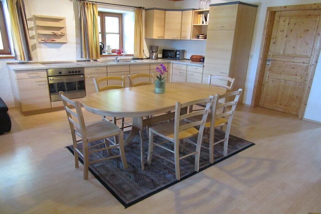 Une cuisine compacte comprenant un coin repas, des meubles de rangement en bois, un four à micro-ondes et un évier.