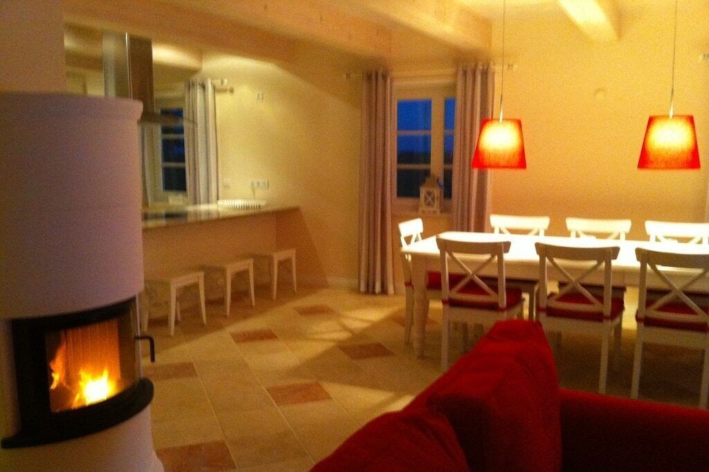 Ein gemütliches Wohnzimmer mit Kamin, einem Essbereich mit weißen Stühlen und einem roten Sofa.