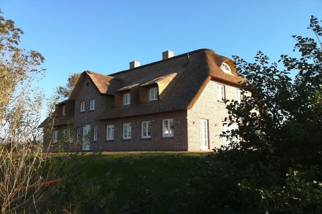 Ein zweistöckiges Haus mit Backsteinfassade, zahlreichen Fenstern und einem geneigten Dach.