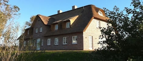 Ein zweistöckiges Haus mit Backsteinfassade, zahlreichen Fenstern und einem geneigten Dach.