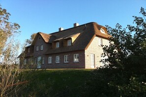 Ein zweistöckiges Haus mit Backsteinfassade, zahlreichen Fenstern und einem geneigten Dach.