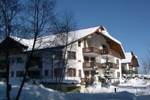 Ett hotell med flera våningar, balkonger och ett snötäckt tak.