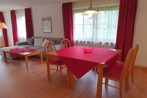 En matplats med ett bord dukat för fyra personer, en soffa och en lampa.