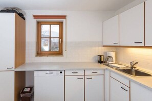 Eine Küche mit weißen Schränken, einem Fenster, einem Geschirrspüler und einer Spüle.