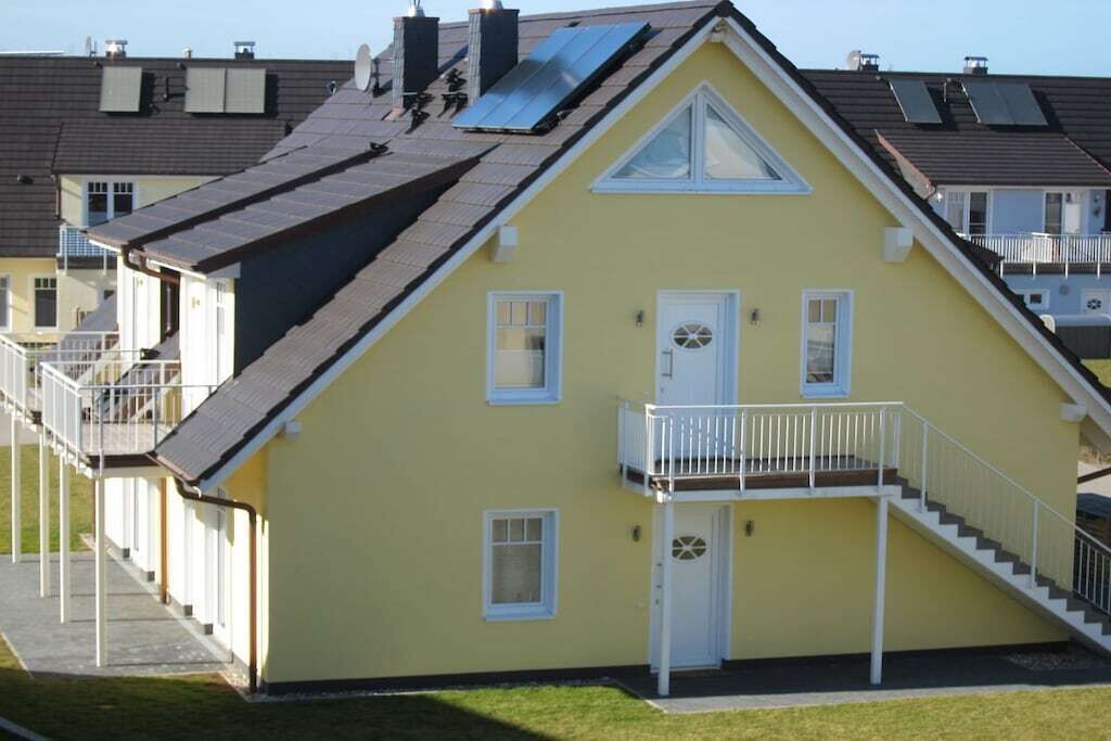 Keltainen rakennus, jossa on parveke, ovi ja portaat, jotka johtavat sisäänkäyntiin.