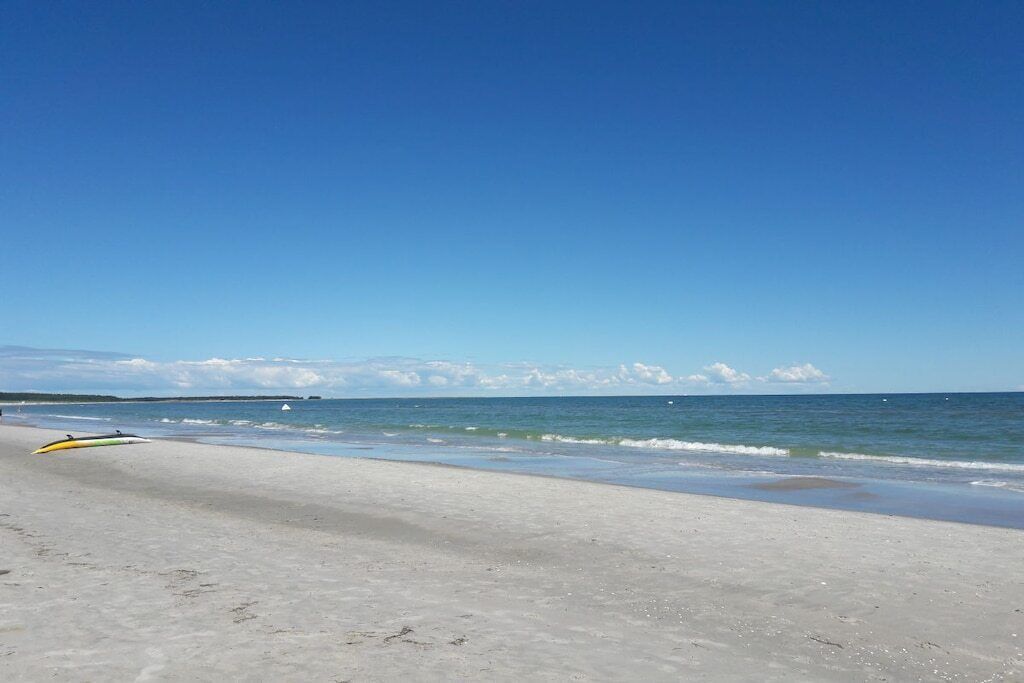 A beach with a surfboard and a clear blue sky.
