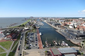 A marina with boats docked, a parking area, and a cityscape in the background. - Chalet Belair Schmidt (Wurster Nordseeküste Ortsteil Dorum-Neufeld)
