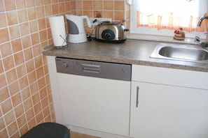 Een praktische keuken met een vaatwasser, een broodrooster en een waterkoker op het aanrecht.