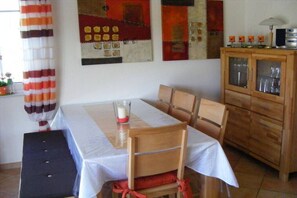 A dining area with a table set for four, wooden chairs, a cabinet with glass doors, and a striped curtain. - Chalet Belair Schmidt (Wurster Nordseeküste Ortsteil Dorum-Neufeld)
