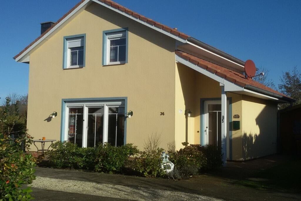 Une maison à deux étages, dotée d’une antenne parabolique, d’un garage et d’un petit jardin.