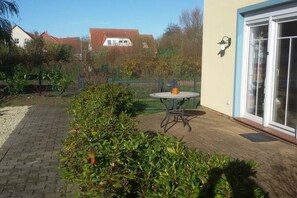 A patio area with a table and chairs, surrounded by greenery and a fence. - Chalet Belair Schmidt (Wurster Nordseeküste Ortsteil Dorum-Neufeld)
