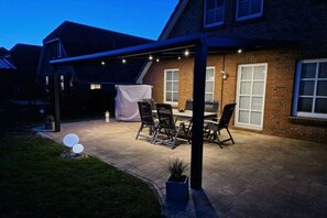 Eine überdachte Terrasse mit Sitzgelegenheit, einem Tisch und Stühlen.