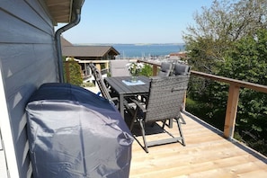 A wooden deck with outdoor furniture, a covered seating area, and a view of the sea. - Baltic Sea harbor view (Langballig)