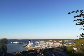 A marina with boats docked, a lighthouse, and buildings in the background. - Baltic Sea harbor view (Langballig)