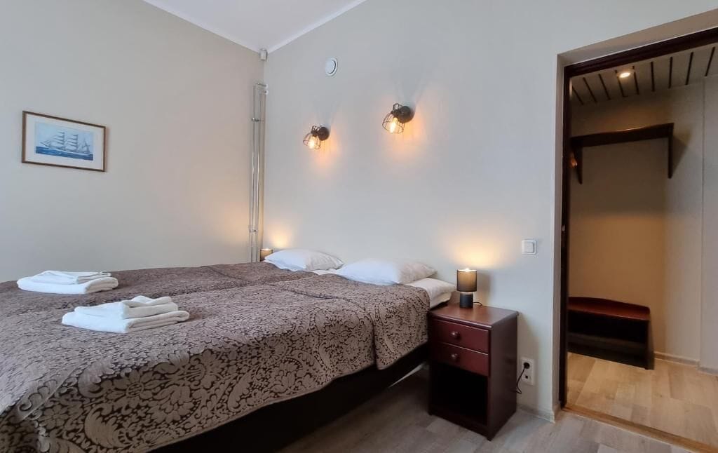 Una habitación de hotel con una cama, mesitas de noche, un armario y un cuadro en la pared.