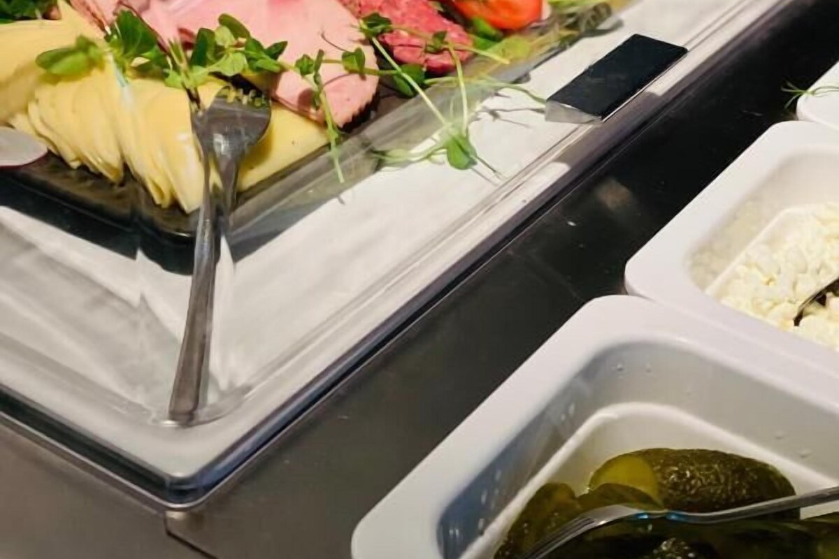 Un bufé con diversos alimentos, incluyendo carnes, verduras y queso.