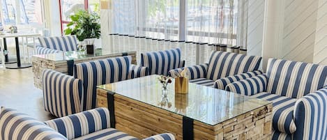 A modern living room with striped sofas, a glass coffee table, and a wooden accent wall.