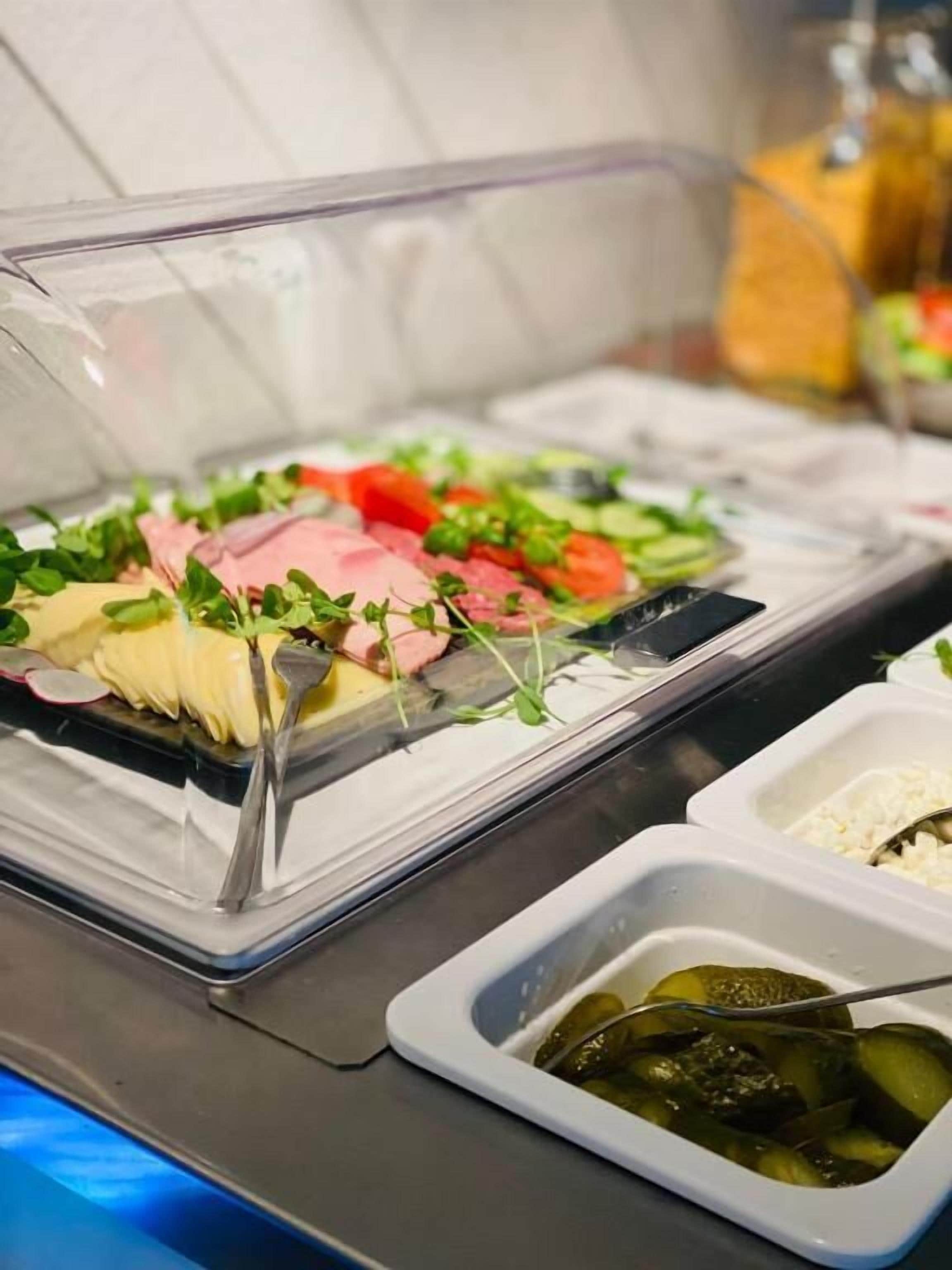 Un buffet proposant une variété de plats, notamment des viandes en tranches, des légumes et du riz.