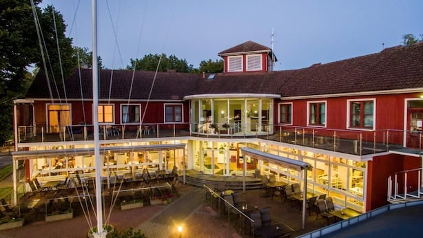 A multi-story building with a dining area on the ground floor and a balcony with seating.