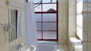 A bathroom with a sink, a bathtub, and a window.