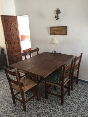Ein Essbereich mit einem Holztisch, Stühlen, einer Lampe und einem gemusterten Boden.
