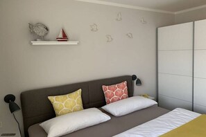 Ein Schlafzimmer mit einem Bett, Kissen, einem Nachttisch, einem Regal mit Dekoration und einem Kleiderschrank.