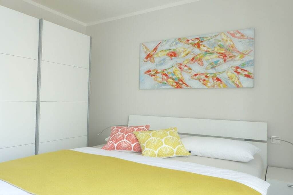 Une chambre à coucher avec un lit, des oreillers, un tableau accroché au mur et une armoire.