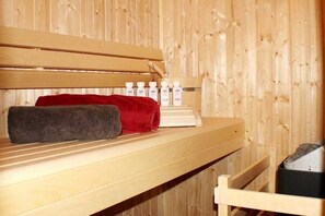 Eine Holzbank mit Handtüchern und Flaschen, vermutlich in einer Sauna oder Dampfbad.